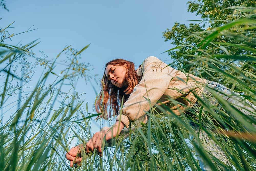A Woman Reaches Into the Tall Grass