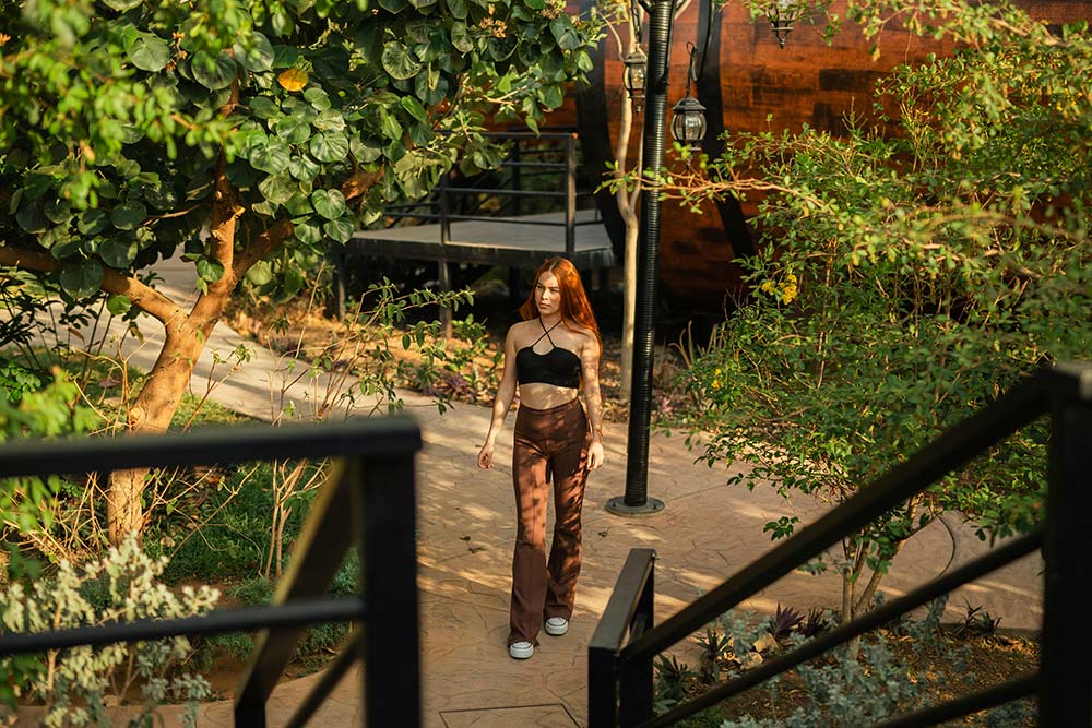 A Woman Walking Down a Sidewalk Next to a Tree