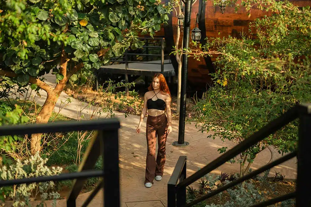 A Woman Walking Down a Sidewalk Next to a Tree