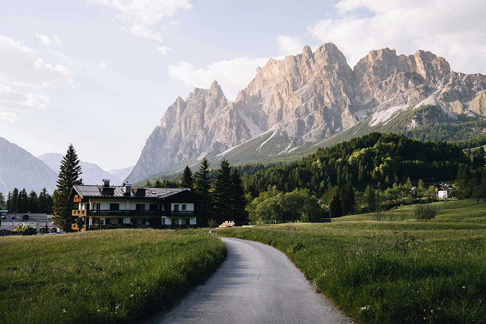 majestic mountains tower over a building and green fields
