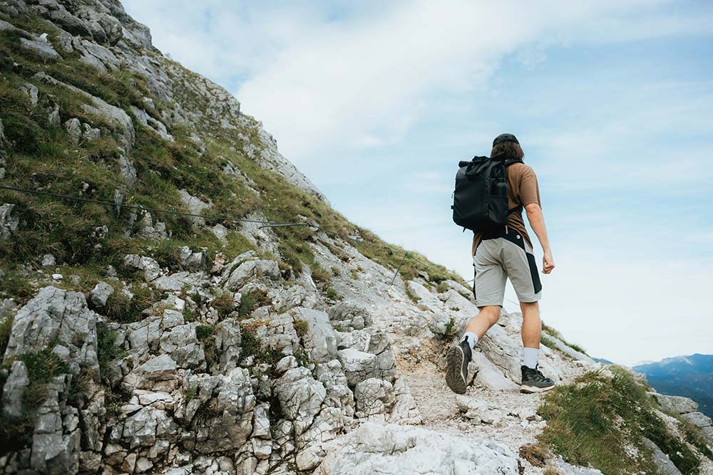 Man with backpack ascending a steep mountain path