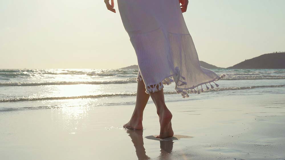 Person walking barefoot on sandy beach